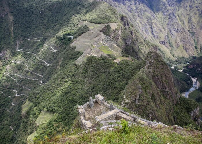 Adventurer climbing the Death Stairs of Huayna Picchu with Machu Picchu ruins below