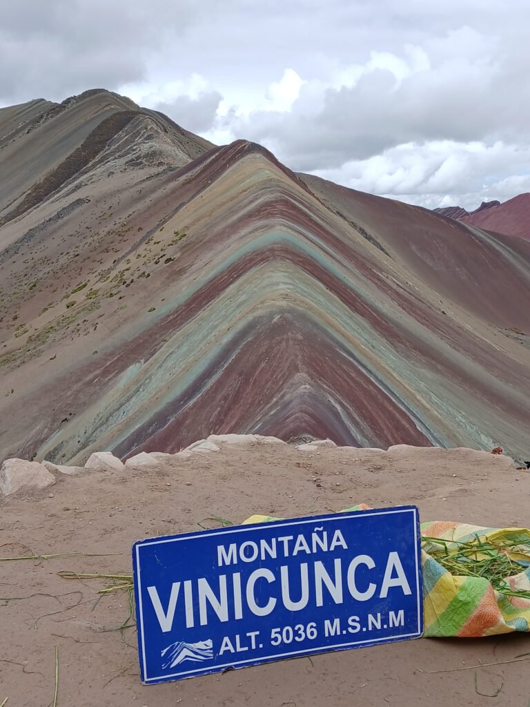 Colorful striped formations of Rainbow Mountain in Peru with visitors on the trail.
